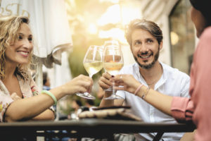 happy friends having fun outdoors - Mid age people enjoying time together at bar - 40s and friendship concept - Hands toasting red and white wine glass at city bar outdoor during sunset