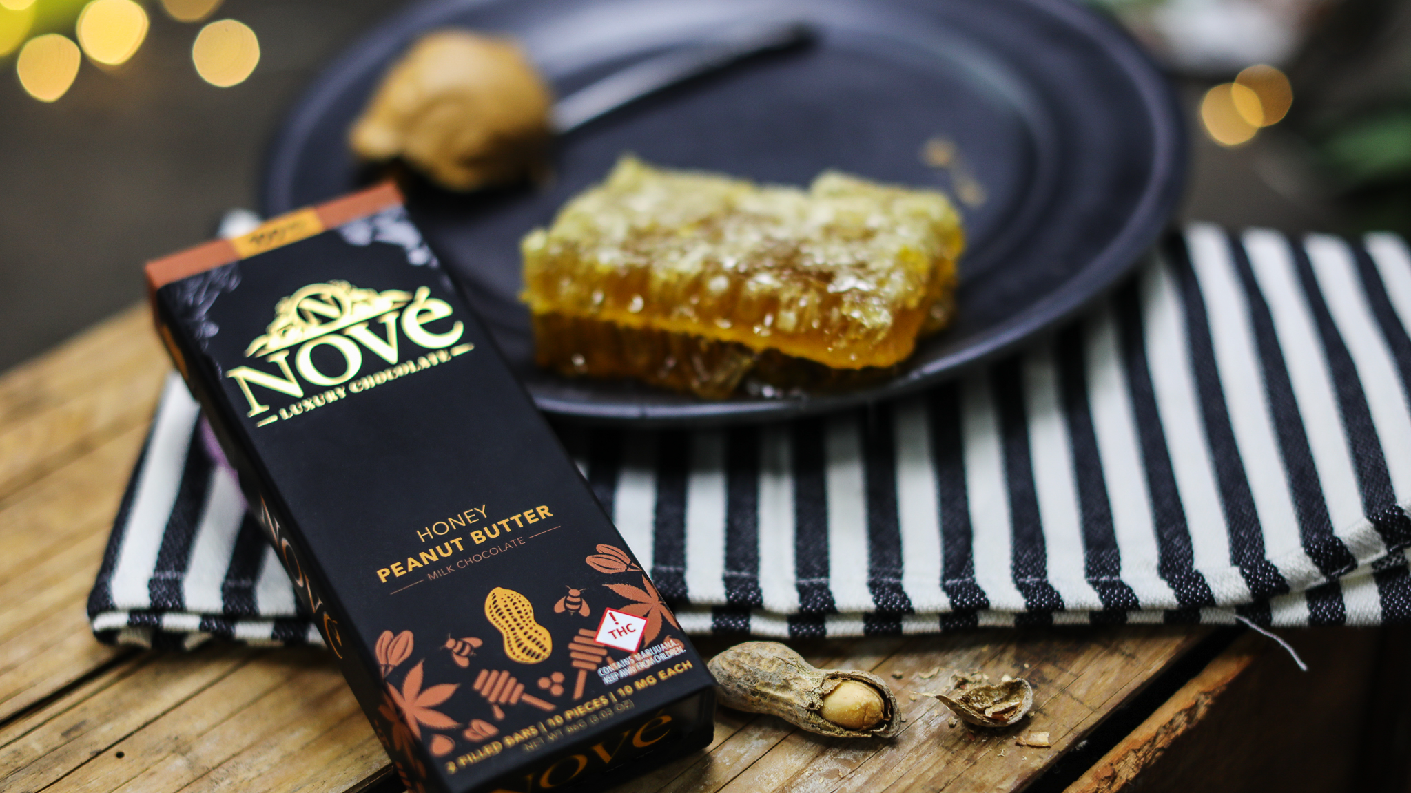 Nove Honey Peanut Butter cannabis chocolate resting next to fresh honeycomb and peanuts.