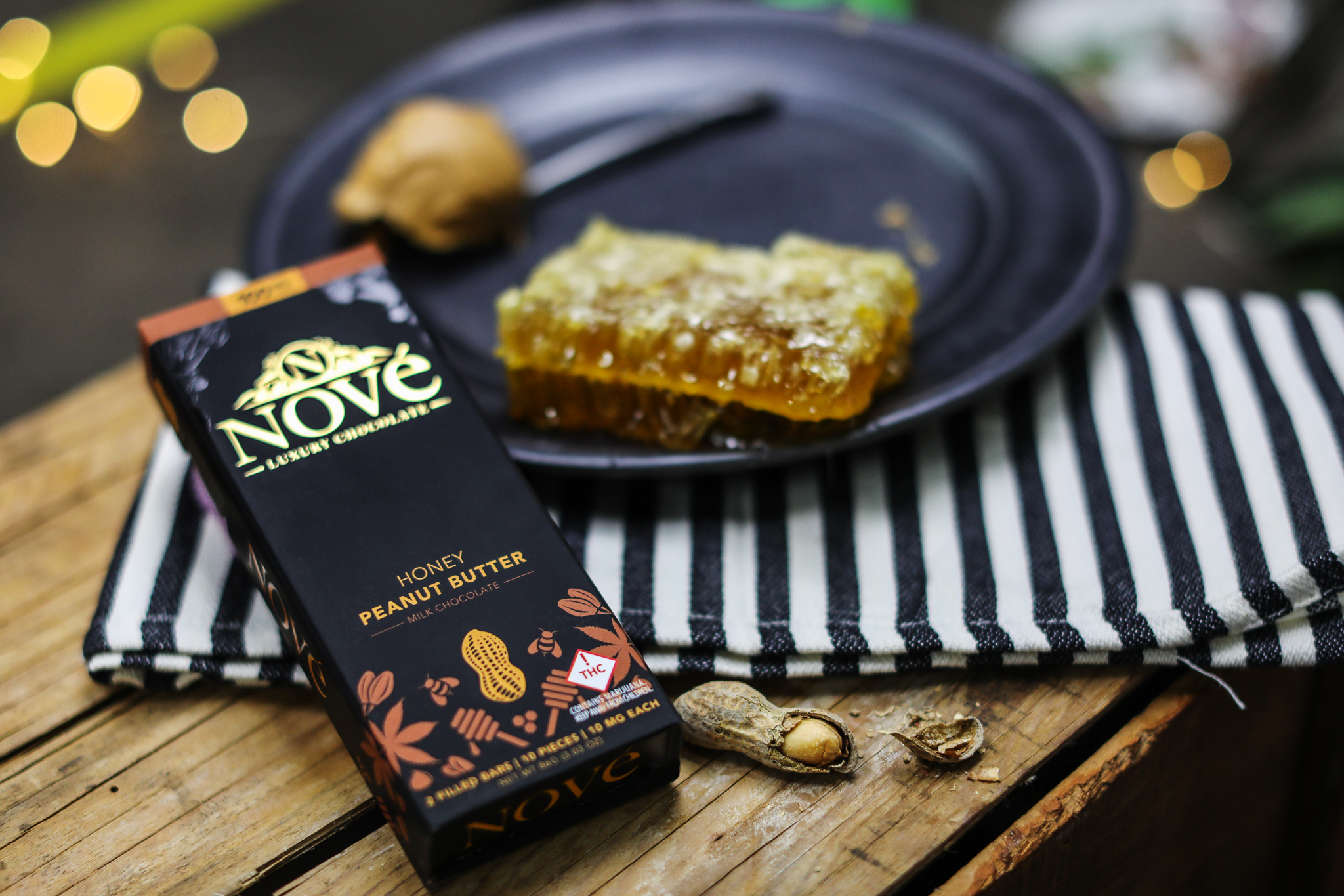 Nove Honey Peanut Butter cannabis chocolate resting next to fresh honeycomb and peanuts.