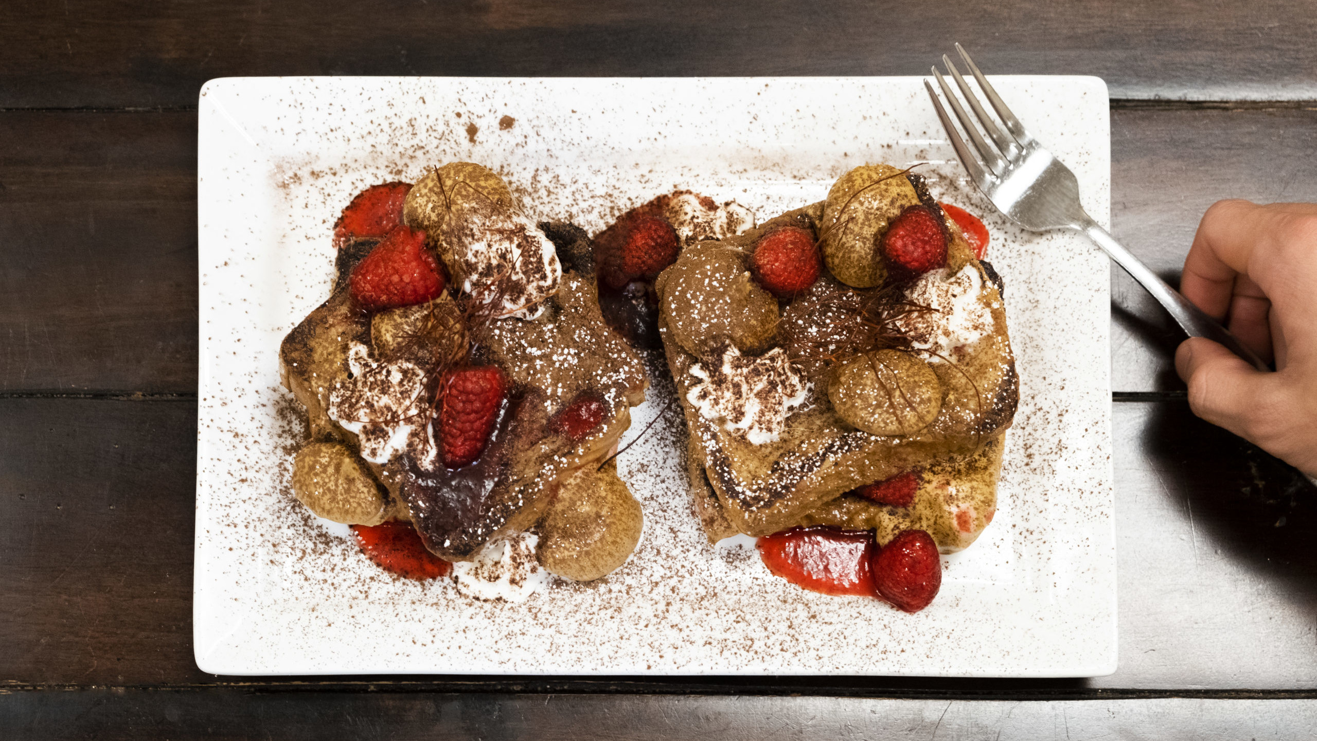 French toast on a white plate, topped with cannabis-infused dalgona coffee cream and spicy raspberry coulis.