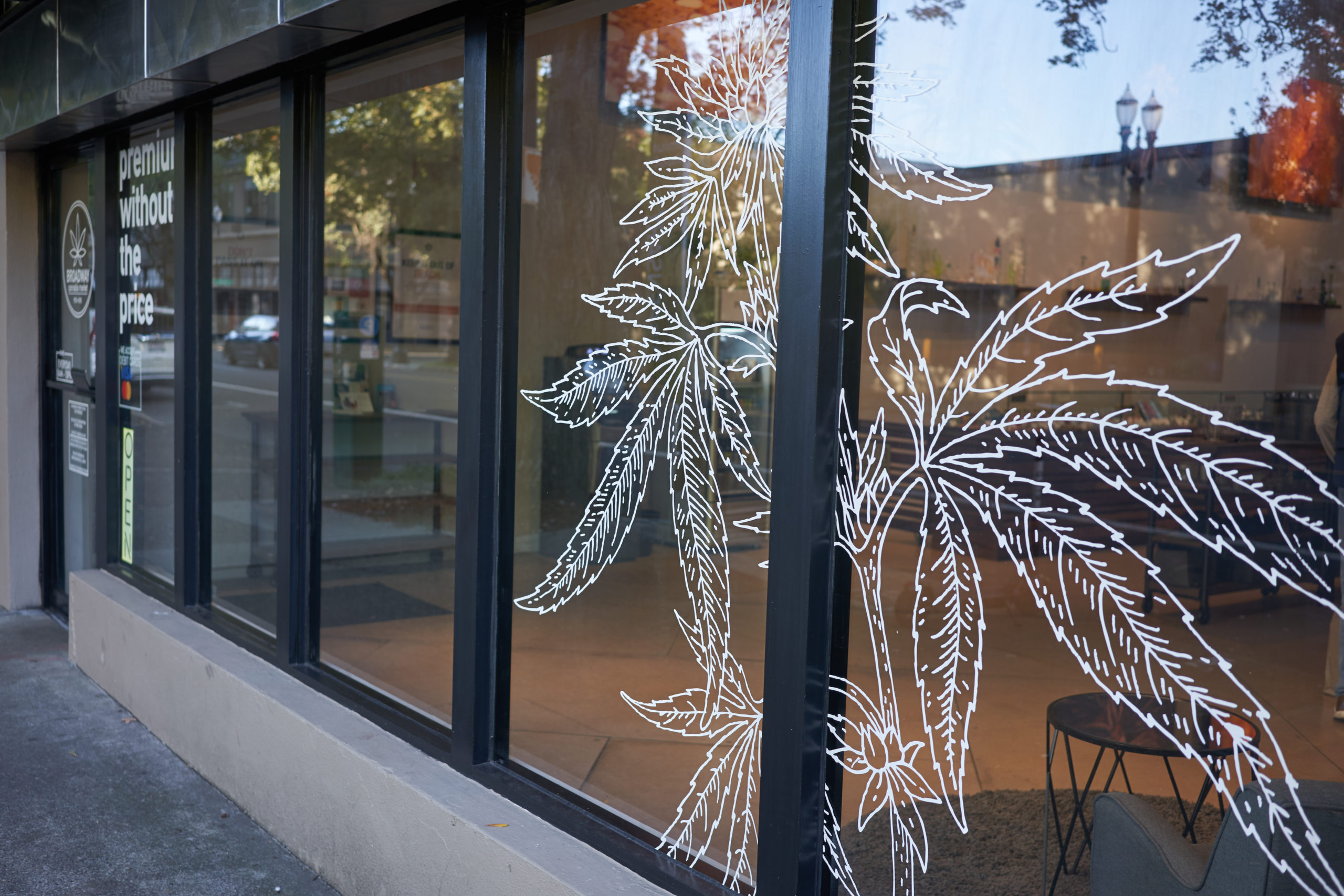 A shot of line-drawn cannabis leaves, posted to the outside windows of a dispensary. Retail workers in the cannabis space are incredible; read nine things budtenders do that most people don't realize.
