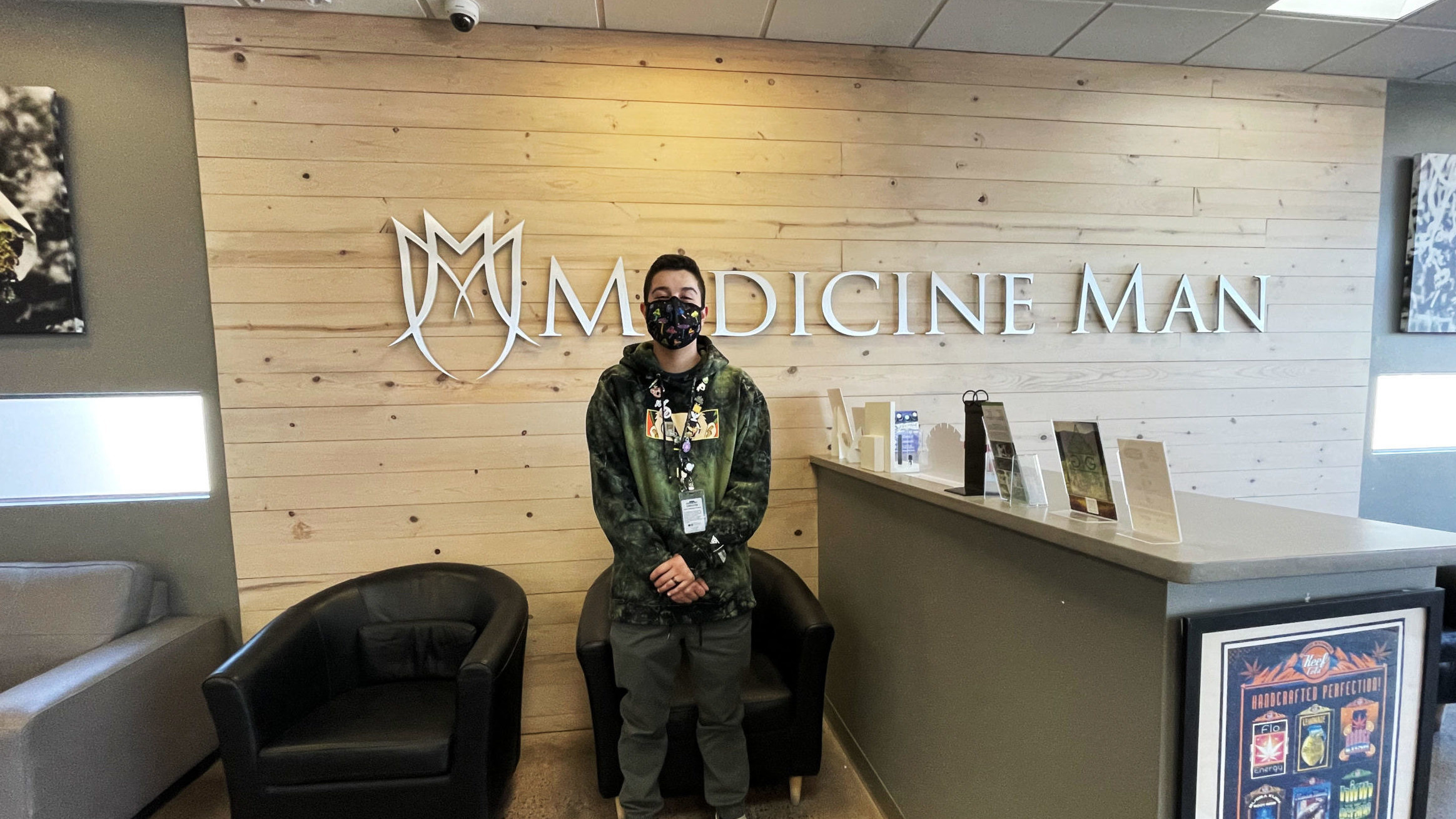 Danny, a budtender at Medicine Man dispensary, reviews Nove chocolates in a recent interview. Here, he stands in front of the Aurora store's logo.