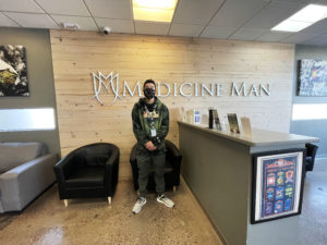 Danny, a budtender at Medicine Man dispensary, reviews Nove chocolates in a recent interview. Here, he stands in front of the Aurora store's logo.